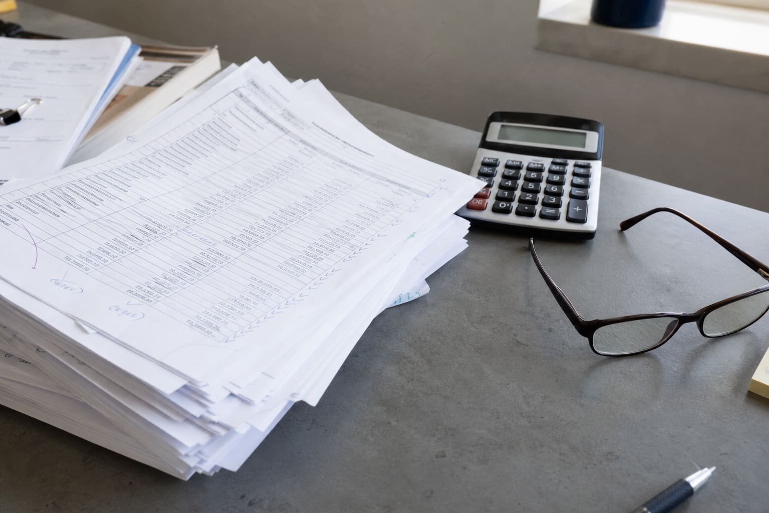 Printed spreadsheet pages and a calculator on a desk in natural light